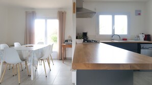 A modern kitchen with a wooden island, white chairs, and a dining table. - New house ideally located in Les Sables d'Olonne (Les Sables-d´Olonne)