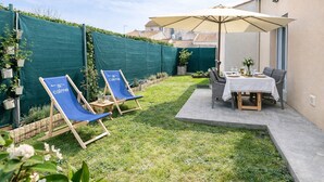 A patio with two blue lounge chairs, a table with a white tablecloth, and an umbrella. - New house ideally located in Les Sables d'Olonne (Les Sables-d´Olonne)