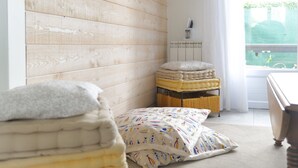 A room with a wooden wall, a radiator, a window with curtains, and a bed with a patterned blanket. - New house ideally located in Les Sables d'Olonne (Les Sables-d´Olonne)