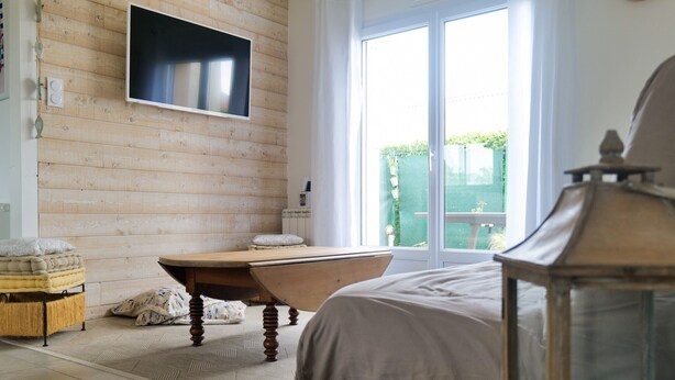 A bedroom with a wooden wall, a bathtub, a bed, and a large window. - New house ideally located in Les Sables d'Olonne (Les Sables-d´Olonne)