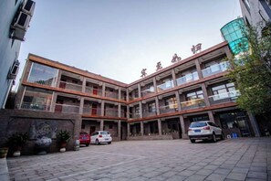 A multi-story building with a courtyard, parking area, and a visible entrance. - Yesanpo Hostel (Laishui)