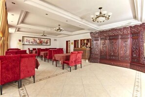 A hotel lobby with red upholstered chairs, a reception desk, and a decorative wooden panel. - Yesanpo Hostel (Laishui)