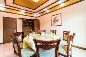 A dining area with a round table, chairs, and a vase of flowers. - Yesanpo Hostel (Laishui)