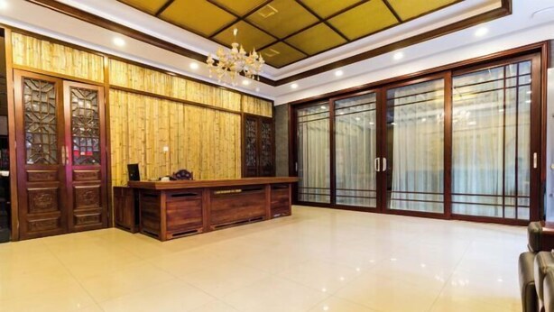 A reception area with a wooden reception desk, a chandelier, and large sliding glass doors. - Yesanpo Hostel (Laishui)