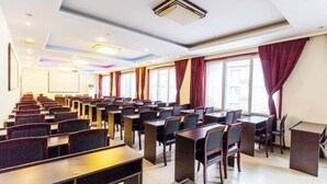A conference room with rows of tables and chairs, a podium, and large windows with curtains. - Yesanpo Hostel (Laishui)