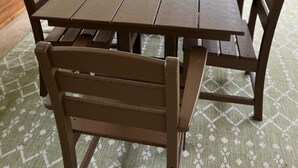 Une table en bois, entourée de six chaises, se trouve dans une pièce dotée de grandes fenêtres.