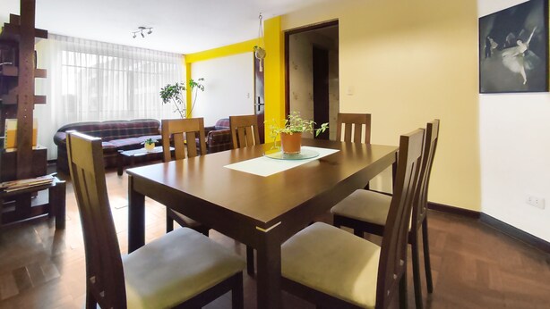 Un espace repas comprenant une table en bois, des chaises et un luminaire suspendu.