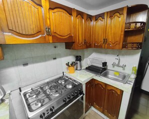A kitchen with wooden cabinets, a gas stove, a sink, and a coffee maker.