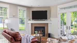 A living room with a fireplace, a television, and comfortable seating. - Waterfront Condo, Pool, Walk to Downtown (Saugatuck)