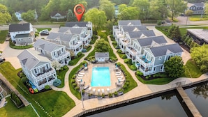 A residential complex with multiple two-story houses, a central swimming pool, and a dock extending into a body of water. - Waterfront Condo, Pool, Walk to Downtown (Saugatuck)