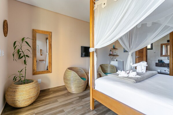 A bedroom with a four-poster bed, a large mirror, and a potted plant.