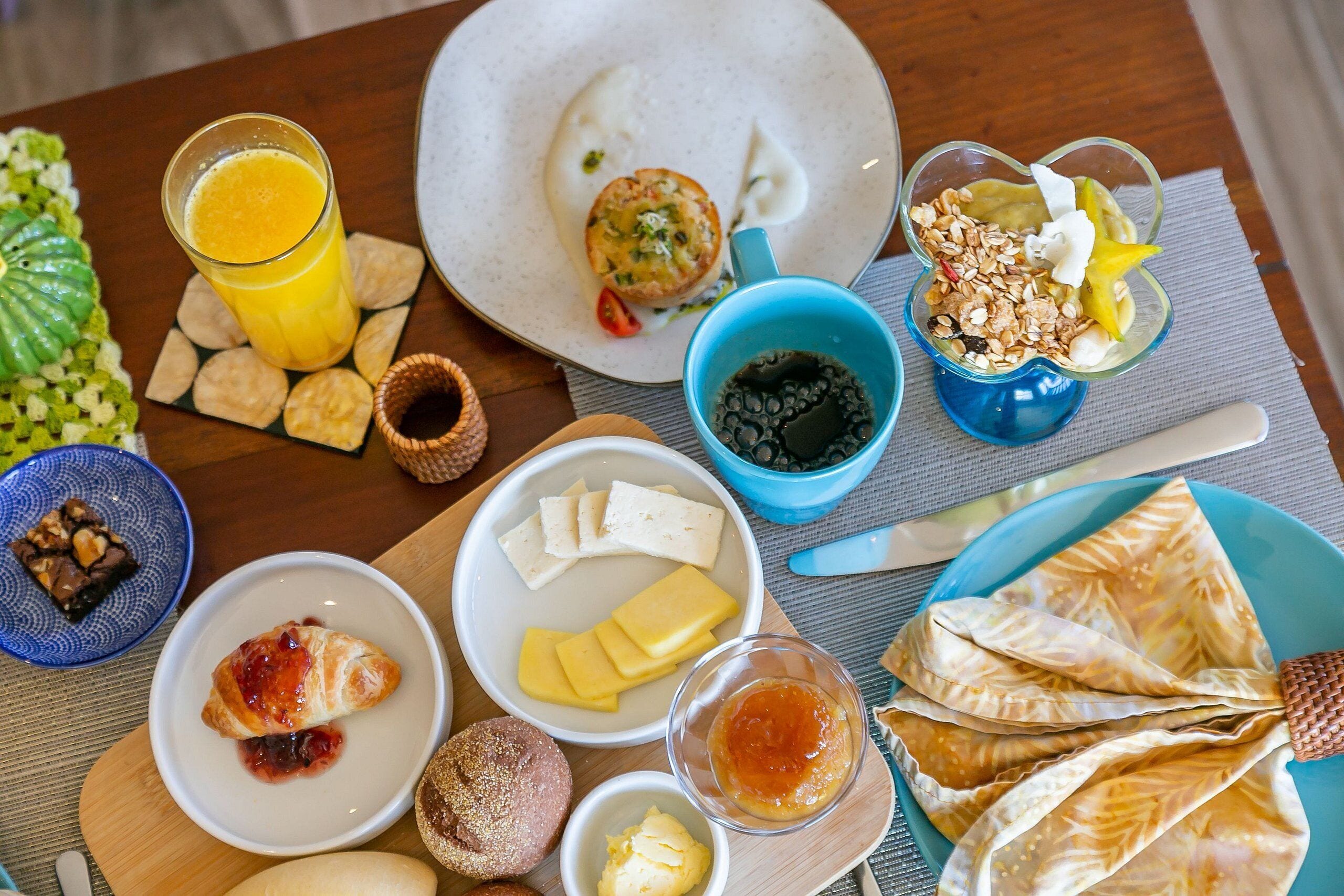 Una mesa de desayuno con diversos alimentos, incluyendo tostadas, huevos y un vaso de jugo de naranja.