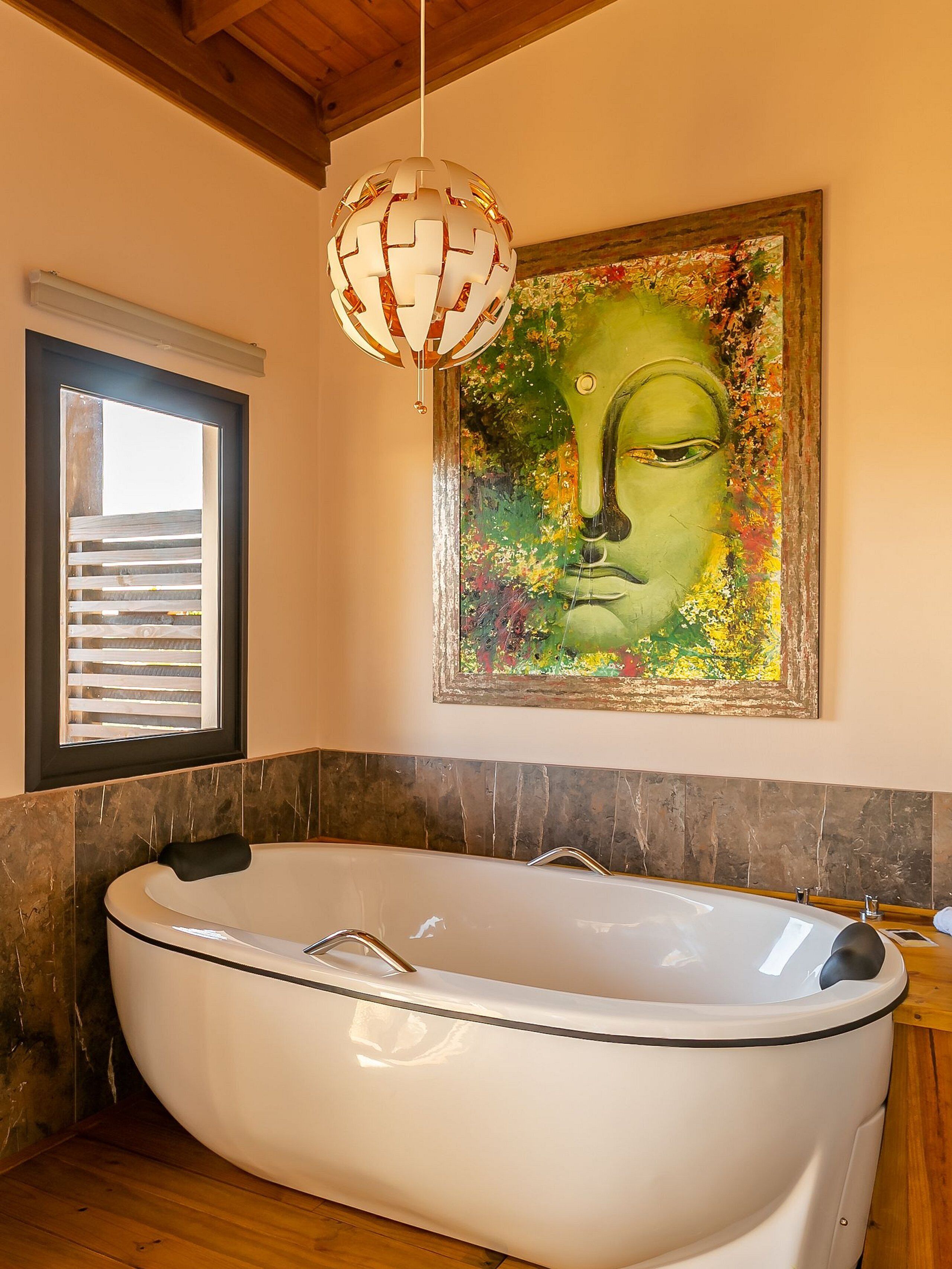 Un baño moderno con una bañera independiente, un cuadro abstracto grande y una lámpara colgante.