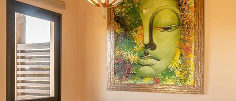 Un baño moderno con una bañera independiente, un cuadro abstracto grande y una lámpara colgante.