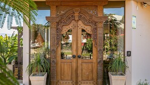 The entrance to Shiva Boutique Hotel with a wooden double door and a sign above it. - Shiva Boutique Hotel - Praia do Rosa (Imbituba)