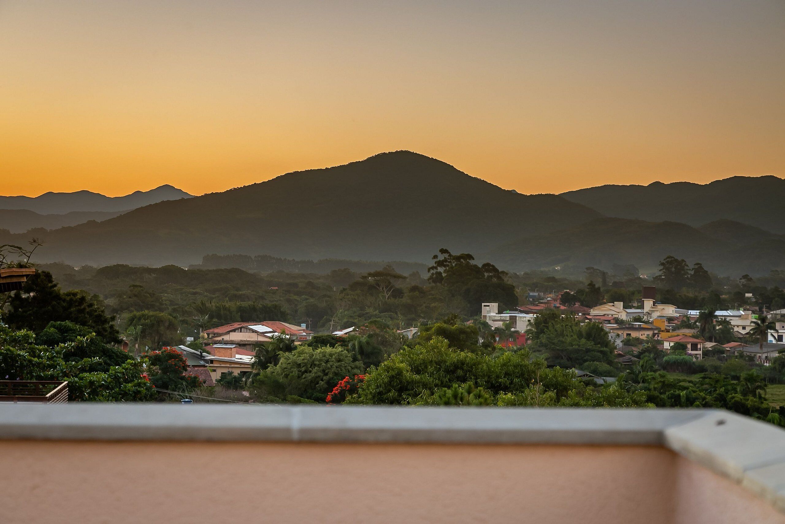A view of a mountain range at sunset with a residential area in the foreground.