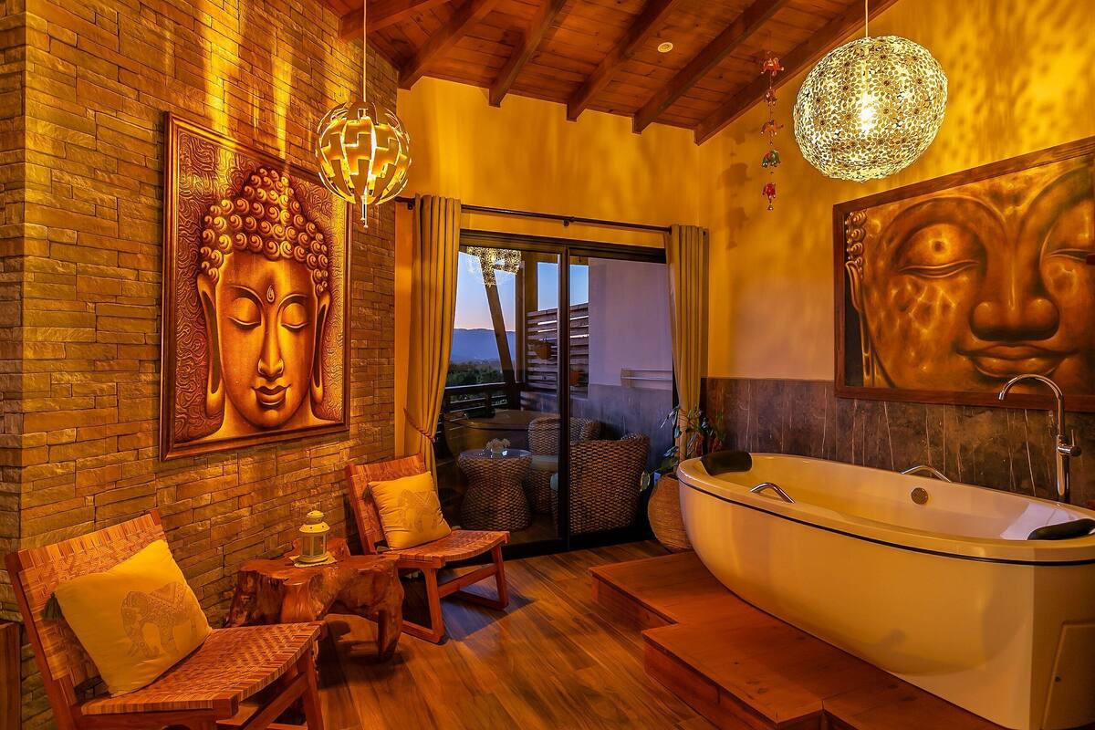 A spa room with a large bathtub, wooden furniture, and Buddha-themed artwork.