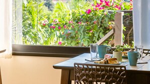 A dining area with a table set for two, a hanging light fixture, and a view of a mountainous landscape through a window. - Shiva Boutique Hotel - Praia do Rosa (Imbituba)