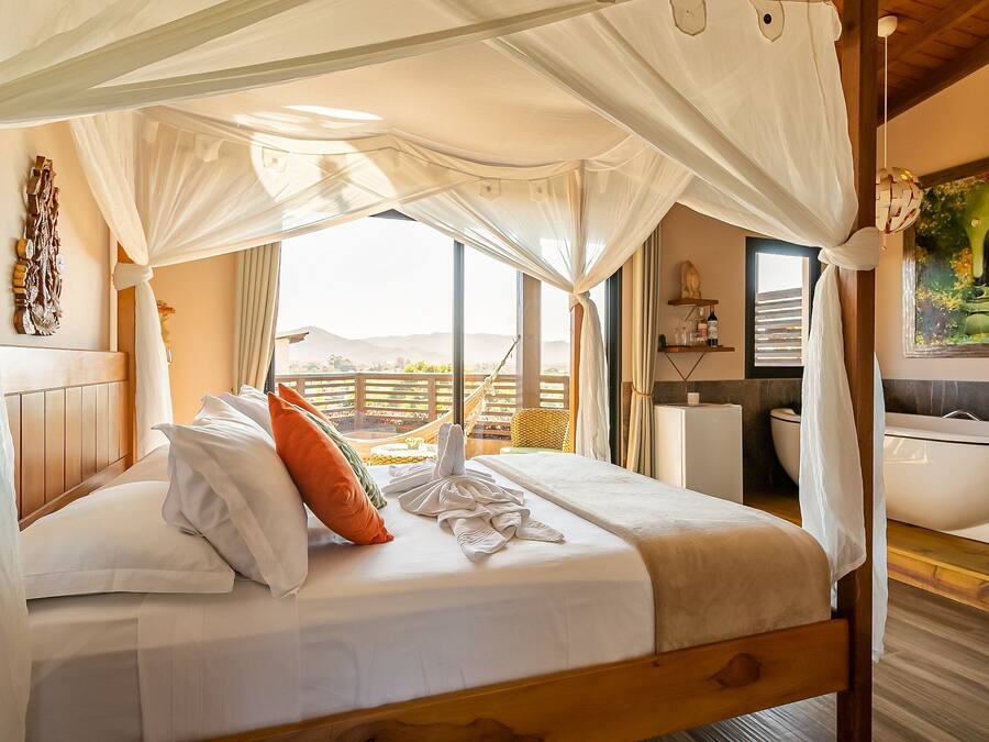 Una cama con dosel, vistas a la montaña, un cuadro y un baño con bañera.
