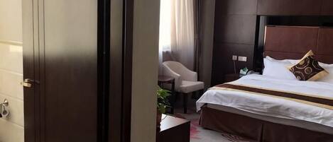 Une chambre d’hôtel avec un lit, une chaise, un bureau et une fenêtre avec des rideaux.