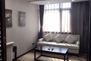 Uma sala de estar com sofá, mesa de centro e janela com cortinas.