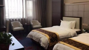 A hotel room with two beds, a small table, two chairs, and a potted plant. - Mengzhiyuan Business Leisure Hotel (Danyang)