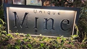 A sign with the word "Unique" and "Mine" in large letters, surrounded by greenery.