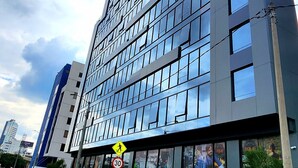 A modern high-rise building with a glass facade, multiple floors, and a pedestrian crossing sign.