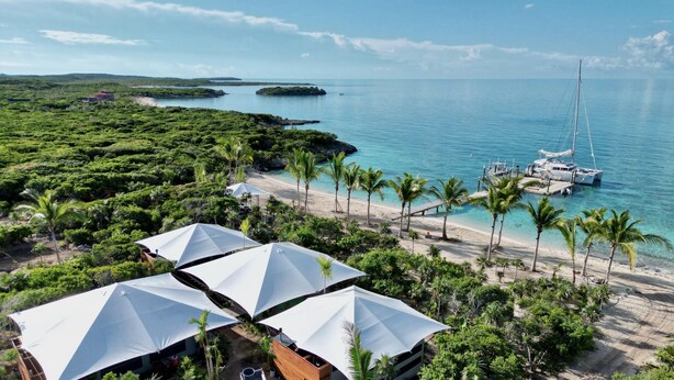 A beachside resort with a marina, palm trees, and a clear view of the ocean. - Luxumas: Unveiling the Extraordinary - All-New, Fully-Staffed Luxury Eco Resort (Exumas)