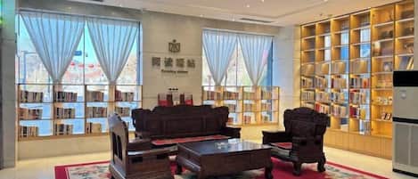 Una biblioteca con un sofá, sillas y una estantería.