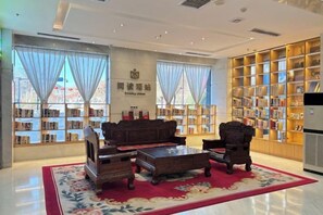 Una biblioteca con un sofá, sillas y una estantería.