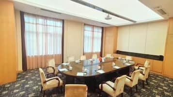 A conference room with a round table, chairs, and a carpeted floor.