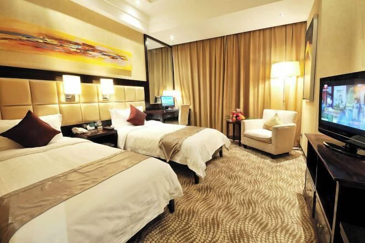 Habitación de hotel con dos camas, un televisor, un escritorio con lámpara y una silla.