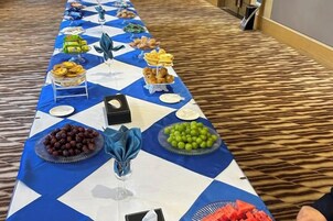 A buffet table with various food items and a blue and white checkered tablecloth.
