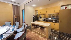 A hotel room with a dining area, a kitchen, and a large window.