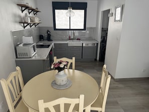 A compact kitchen with a dining area, featuring a microwave, coffee maker, and a vase with flowers on the table. - Charming house with swimming pool (Bessan)