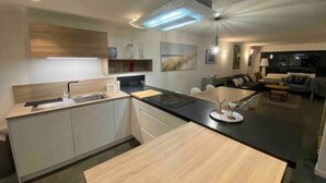 A modern kitchen with a central island, built-in cabinets, and a dining area with a sofa and coffee table.