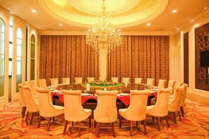 A formal dining room with a round table, multiple chairs, a chandelier, and patterned curtains. - Dexin Resort Hotel (Chongqing)