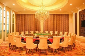 A formal dining room with a round table, chairs, a chandelier, patterned curtains, and a carpeted floor. - Dexin Resort Hotel (Chongqing)