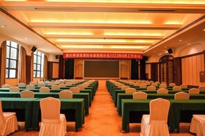 A conference room with rows of tables and chairs, a stage at the front, and a banner above. - Dexin Resort Hotel (Chongqing)