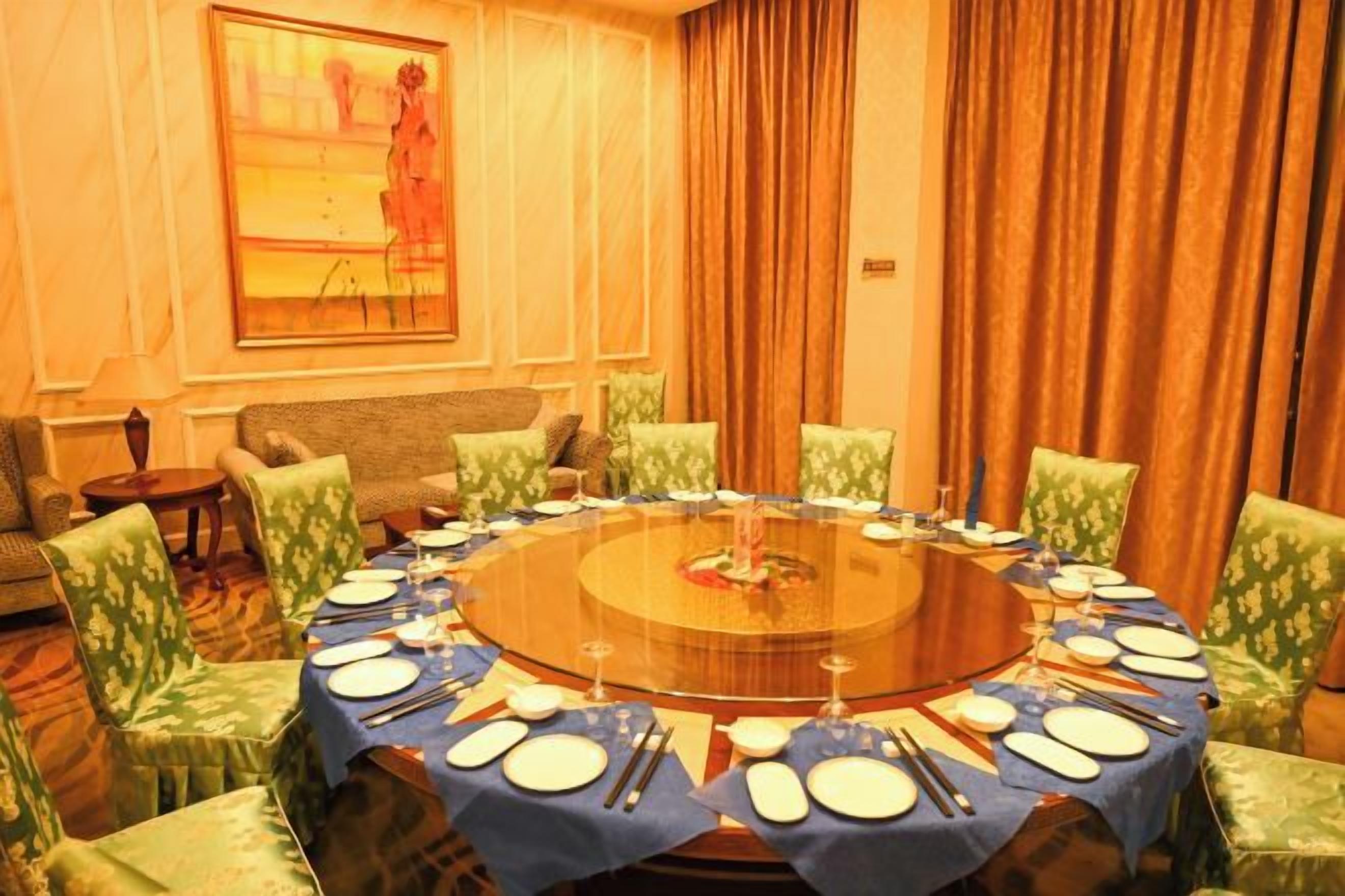 A conference room with a round table, chairs, and a painting on the wall.