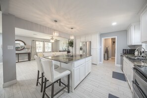 A modern kitchen with a central island, white cabinetry, and stainless steel appliances.