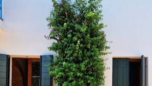 Un edificio con base de ladrillo, sección superior blanca y contraventanas verdes en las ventanas.