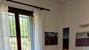 Una habitación con dos camas, un radiador, una silla de madera y dos cuadros en la pared.