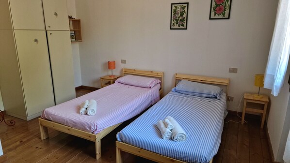 Una habitación con dos camas individuales, cabeceros de madera y un armario.