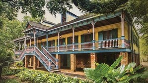 A two-story colonial-style building with a balcony and staircase.