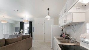 A modern kitchen with a black stovetop, white cabinets, and a stainless steel sink.