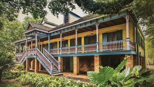 A two-story colonial-style building with a balcony and staircase.
