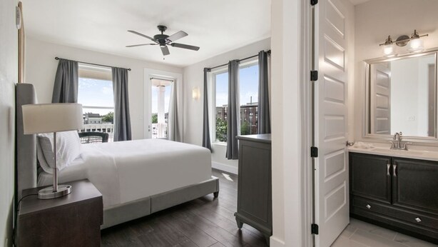 Een hotelkamer met een bed, een dressoir, een spiegel en een plafondventilator.
