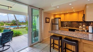 A modern kitchen with a large island, a refrigerator, and a coffee maker.